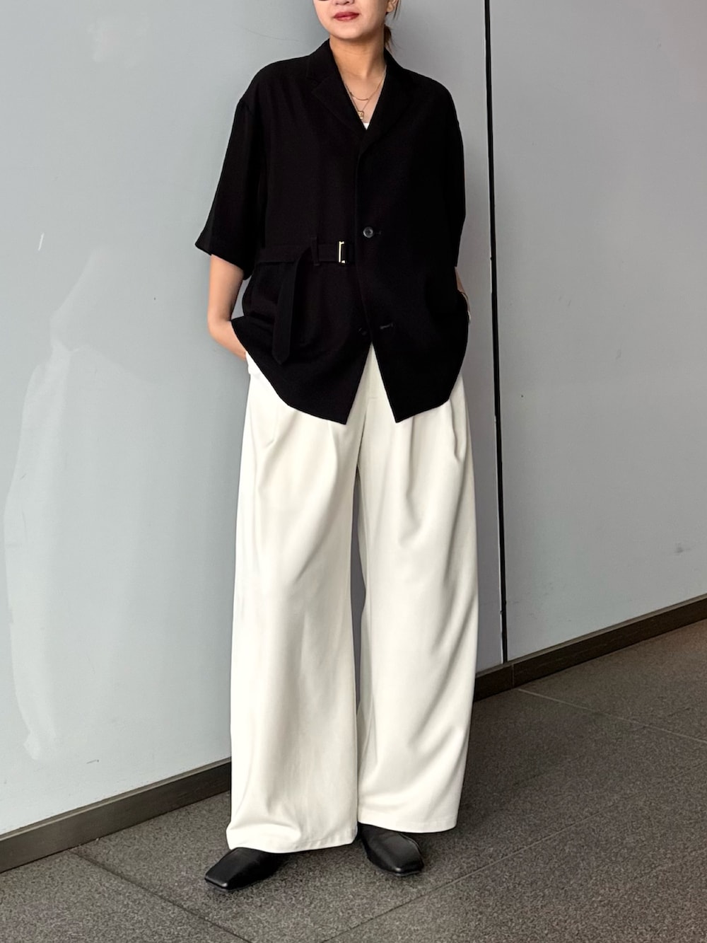 グレー系のスラックス、ブラック系のシャツ/ブラウスを着用したレディースの春コーディネートの2枚目の写真