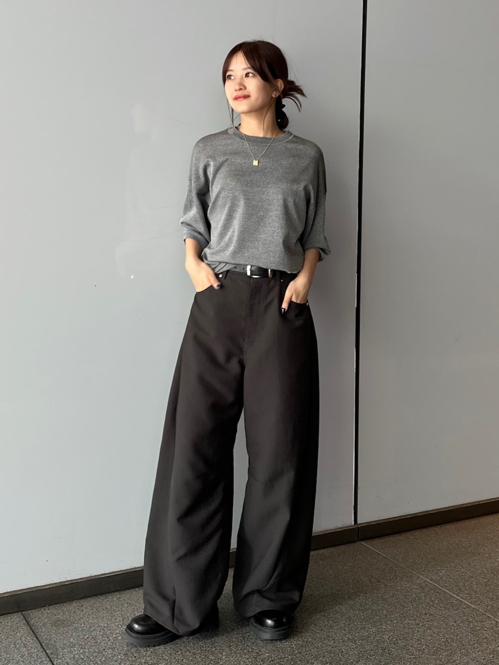 レッド系のニット/セーター、ブラック系のスラックス、ブラック系のブーツを着用したレディースの春コーディネートの2枚目の写真