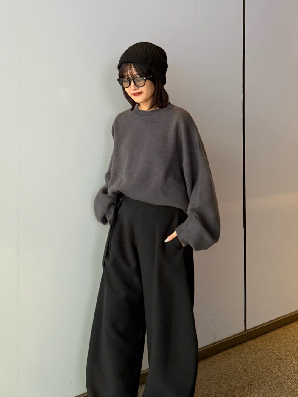 グレー系のニット/セーター、ブラック系のスラックス、ブラック系のサングラスを着用したレディースの秋コーディネートの5枚目の写真