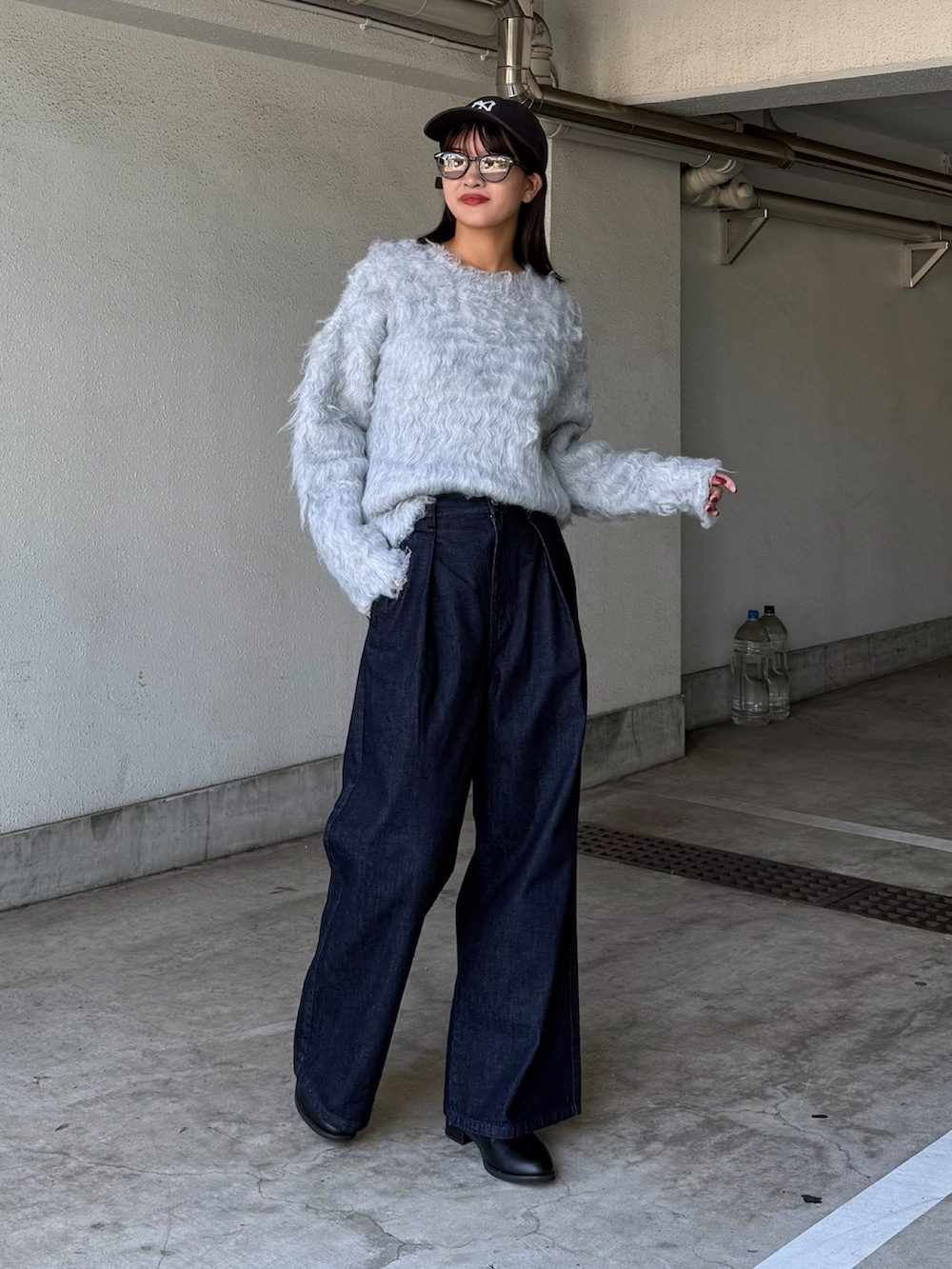 グレー系のニット/セーター、ブルー系のデニムパンツ、ブラック系のサングラスを着用したレディースの秋コーディネートの2枚目の写真