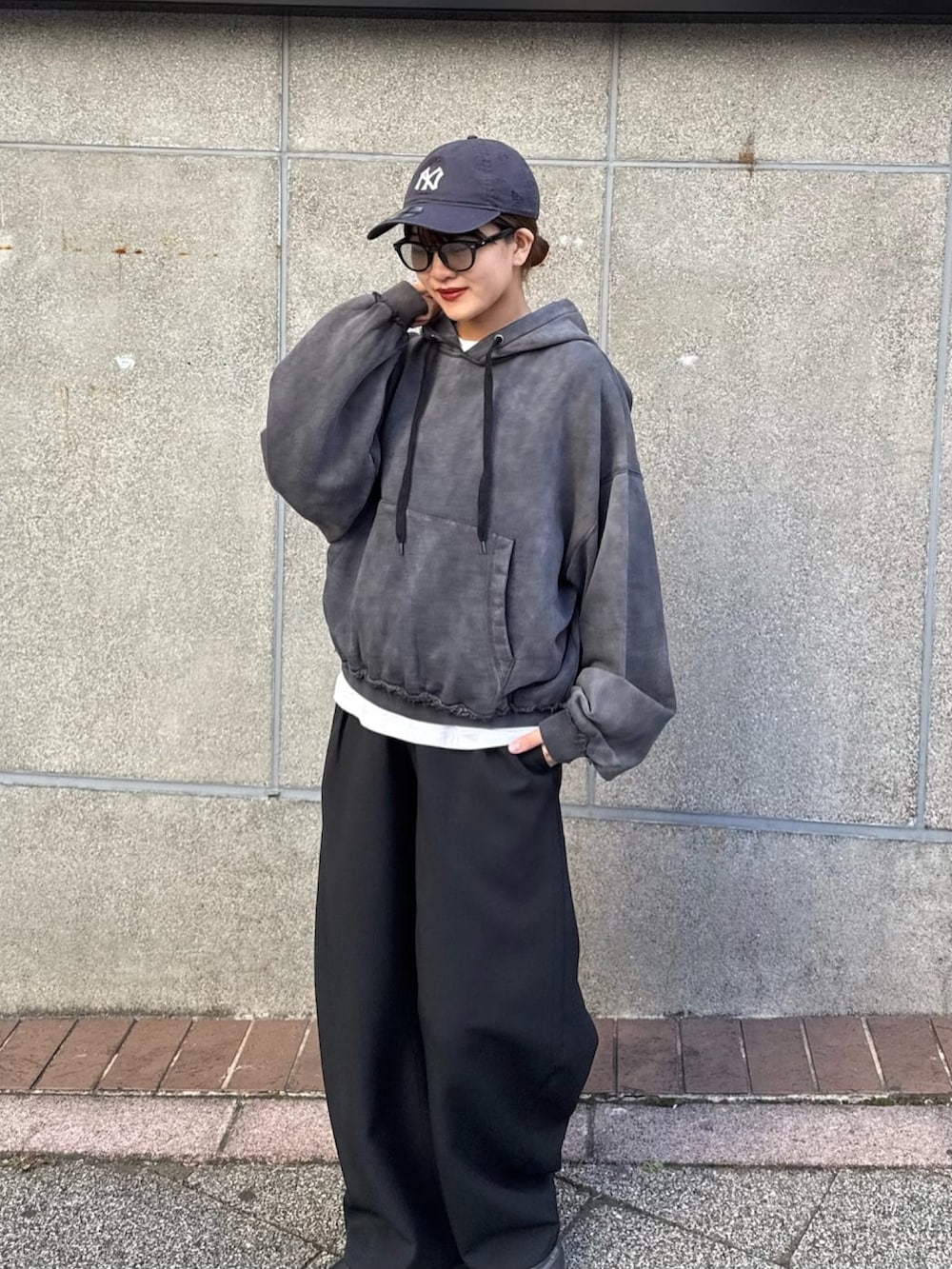 ブラック系のパーカー、ブラック系のスラックス、ブラック系のサングラスを着用したレディースの冬コーディネートの5枚目の写真