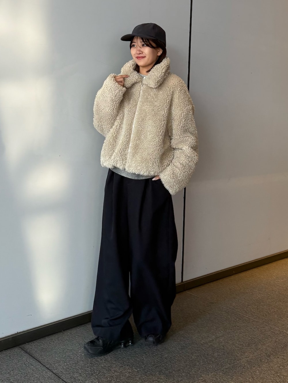 ベージュ系のブルゾン、ブラック系のスラックスを着用したレディースの冬コーディネートの3枚目の写真