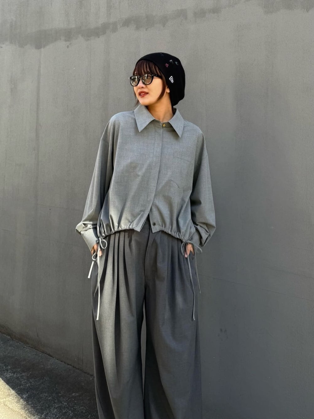 グレー系のスラックス、グレー系のシャツ/ブラウス、ブラック系のサングラスを着用したレディースの冬コーディネートの2枚目の写真