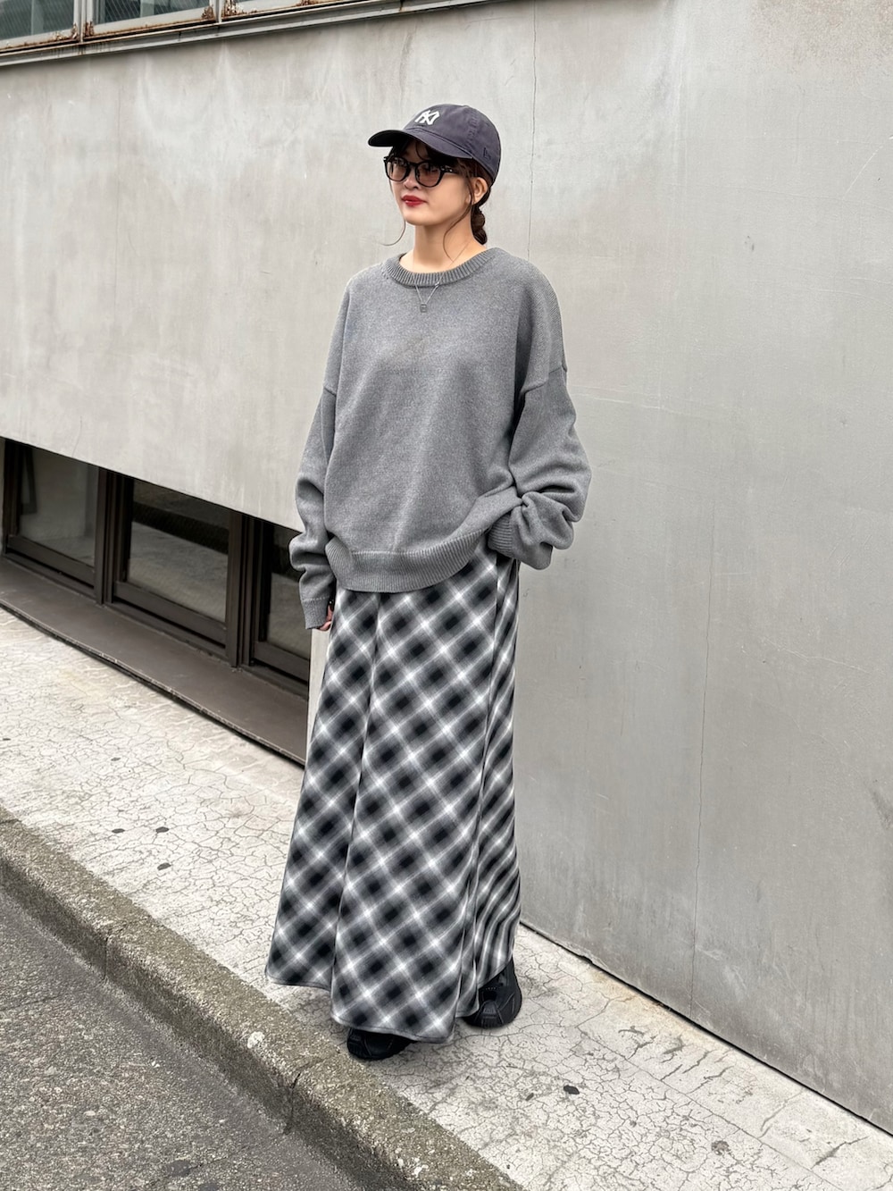 グレー系のニット/セーター、ブラック系のスカート、ブラック系のサングラスを着用したレディースの秋コーディネートの3枚目の写真