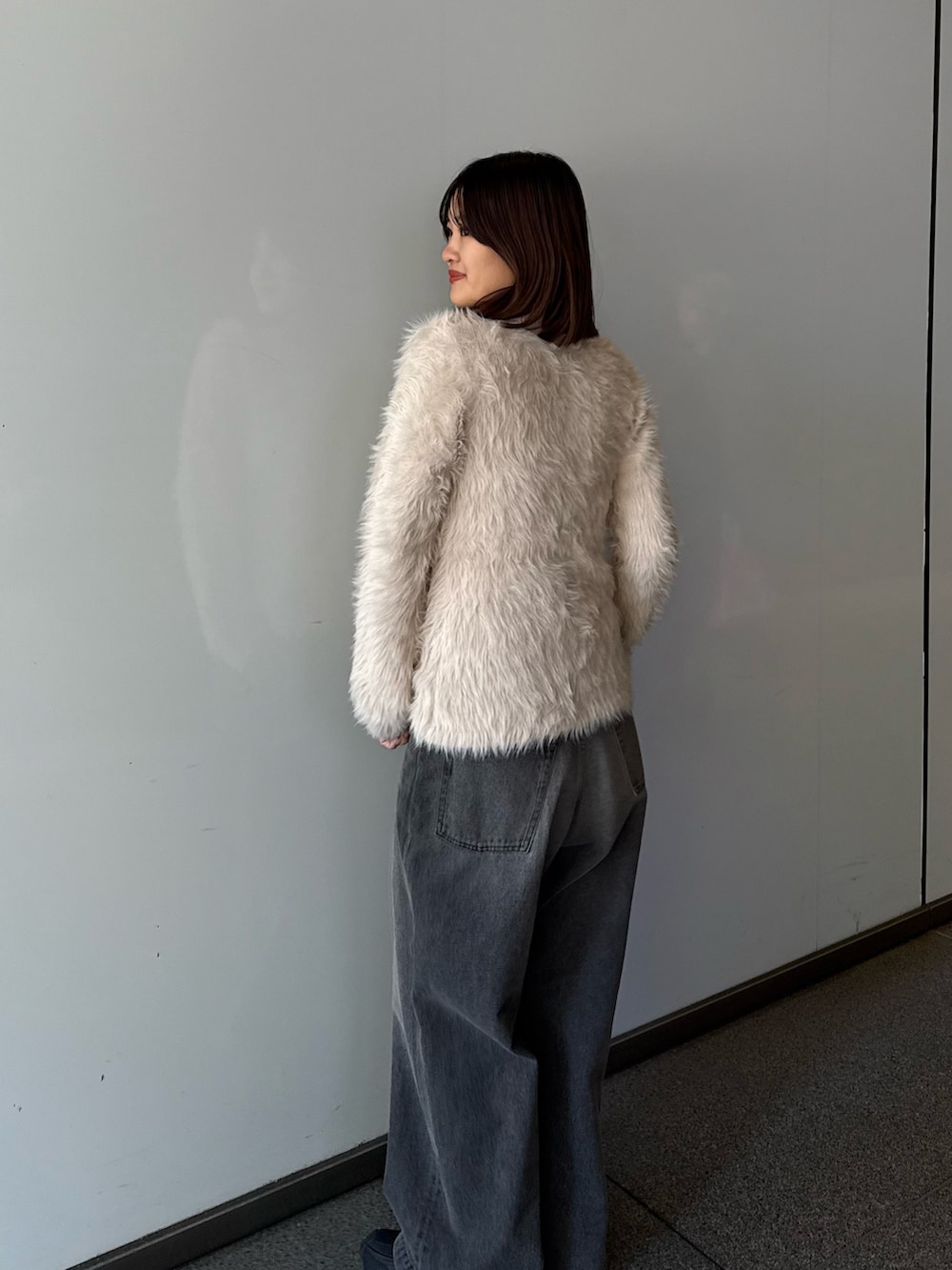 ベージュ系のニット/セーター、ブラック系のデニムパンツを着用したレディースの秋コーディネートの4枚目の写真