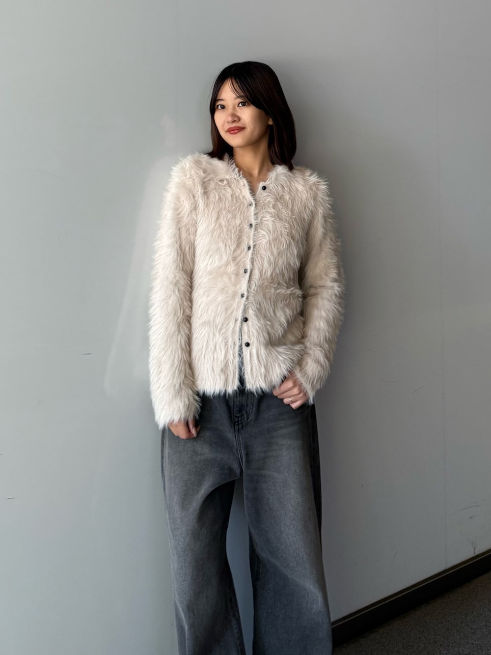 ベージュ系のニット/セーター、ブラック系のデニムパンツを着用したレディースの秋コーディネートの2枚目の写真