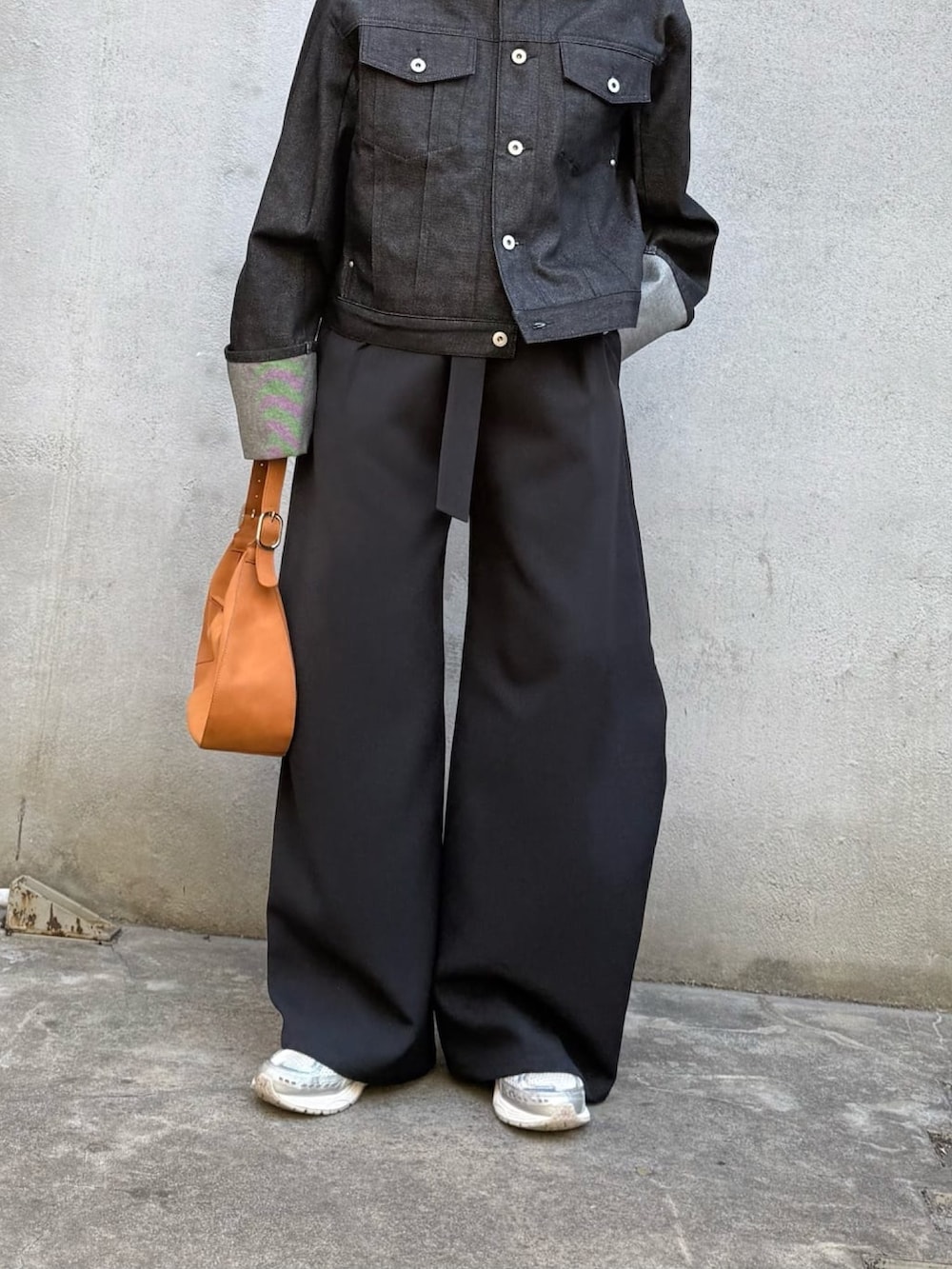 ブラック系のデニムジャケット、ブラック系のスラックス、ブラック系のハンドバッグを着用したレディースの冬コーディネートの2枚目の写真