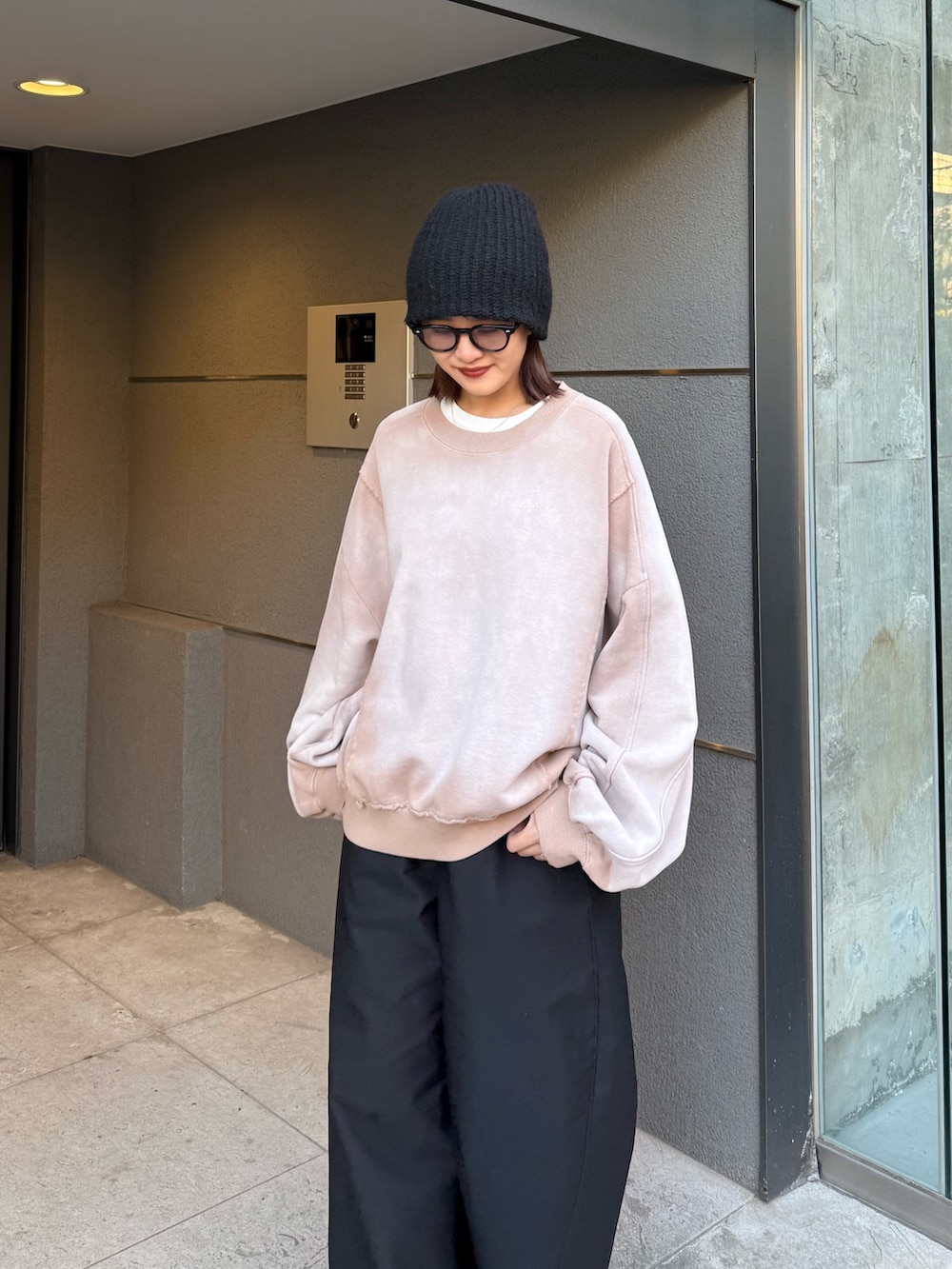 ベージュ系のスウェット、ブラック系のスラックス、ブラック系のサングラスを着用したレディースの冬コーディネートの5枚目の写真