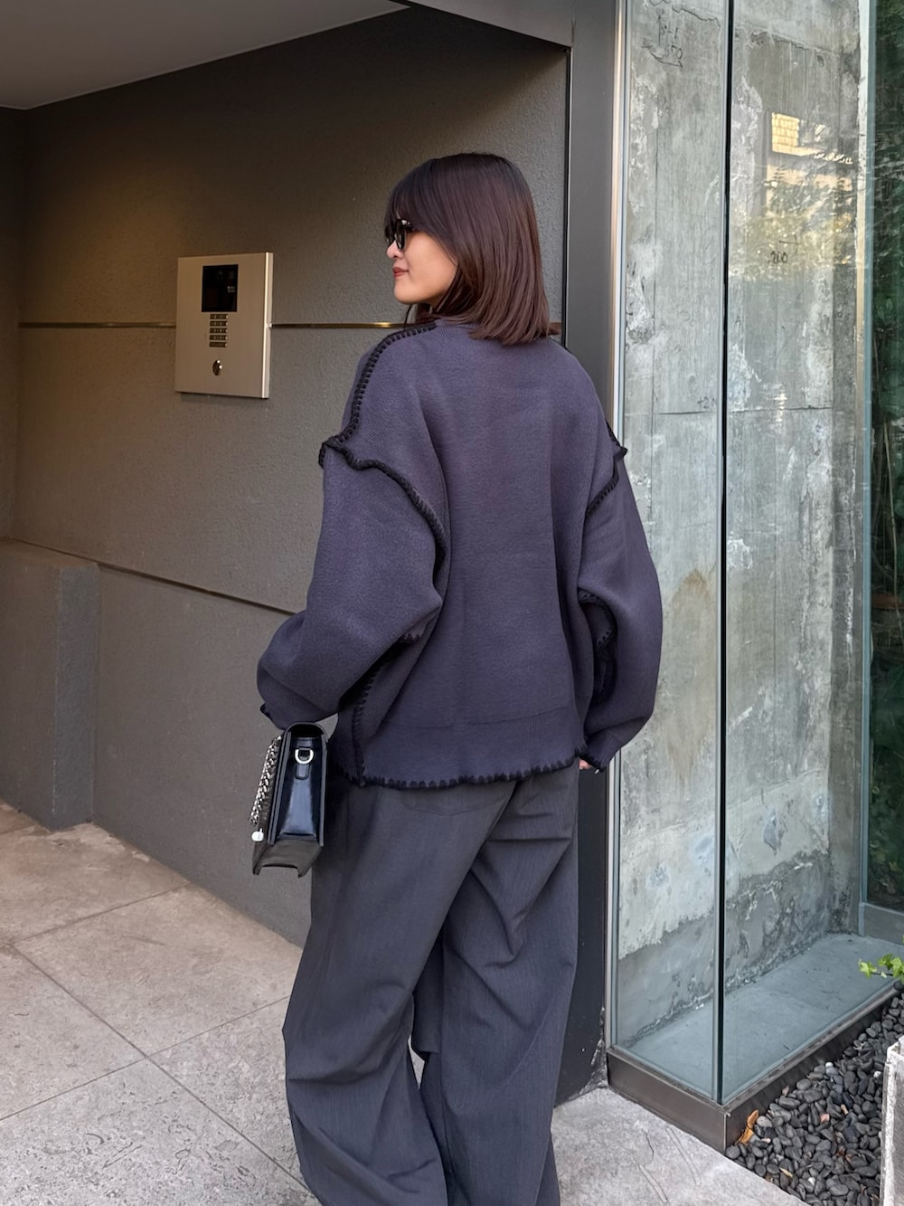 グレー系のニット/セーター、グレー系のスラックス、ブラック系のショルダーバッグを着用したレディースの冬コーディネートの5枚目の写真