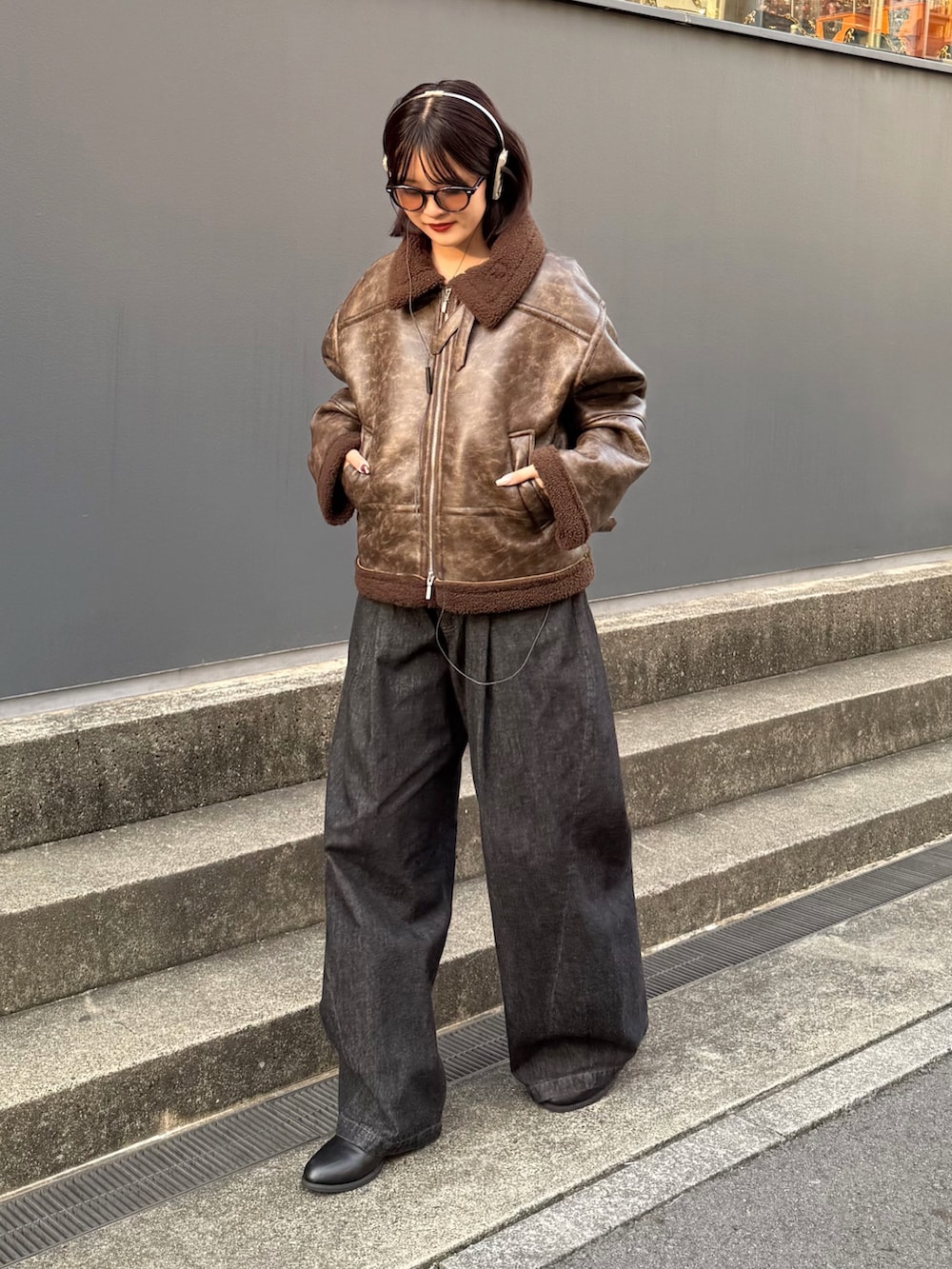 ブラウン系のブルゾン、ブラック系のデニムパンツを着用したレディースの秋コーディネートの2枚目の写真