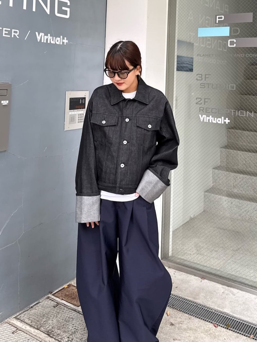 ブルー系のその他パンツ、ブラック系のデニムジャケット、ブラック系のサングラスを着用したレディースの春コーディネートの2枚目の写真