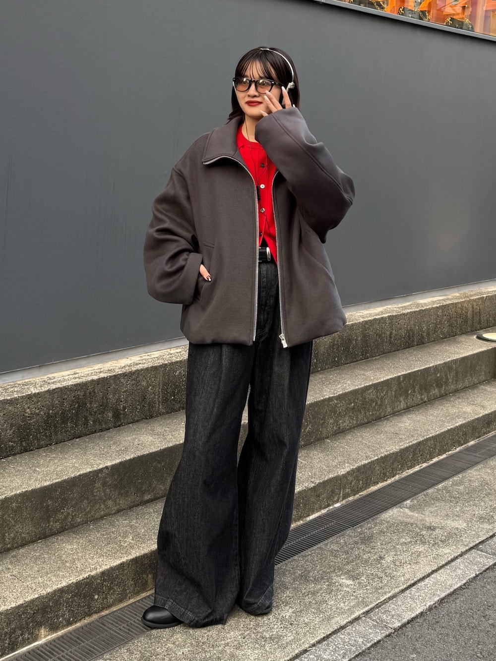 グレー系のブルゾン、レッド系のカーディガン/ボレロ、ブラック系のデニムパンツを着用したレディースの秋コーディネートの8枚目の写真