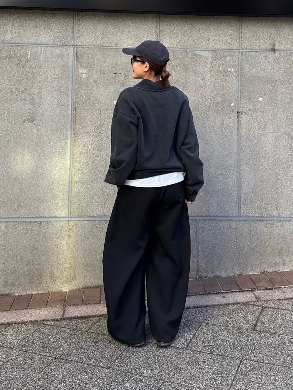 ブラック系のスウェット、ブラック系のスラックス、ブラック系のサングラスを着用したレディースの冬コーディネートの5枚目の写真