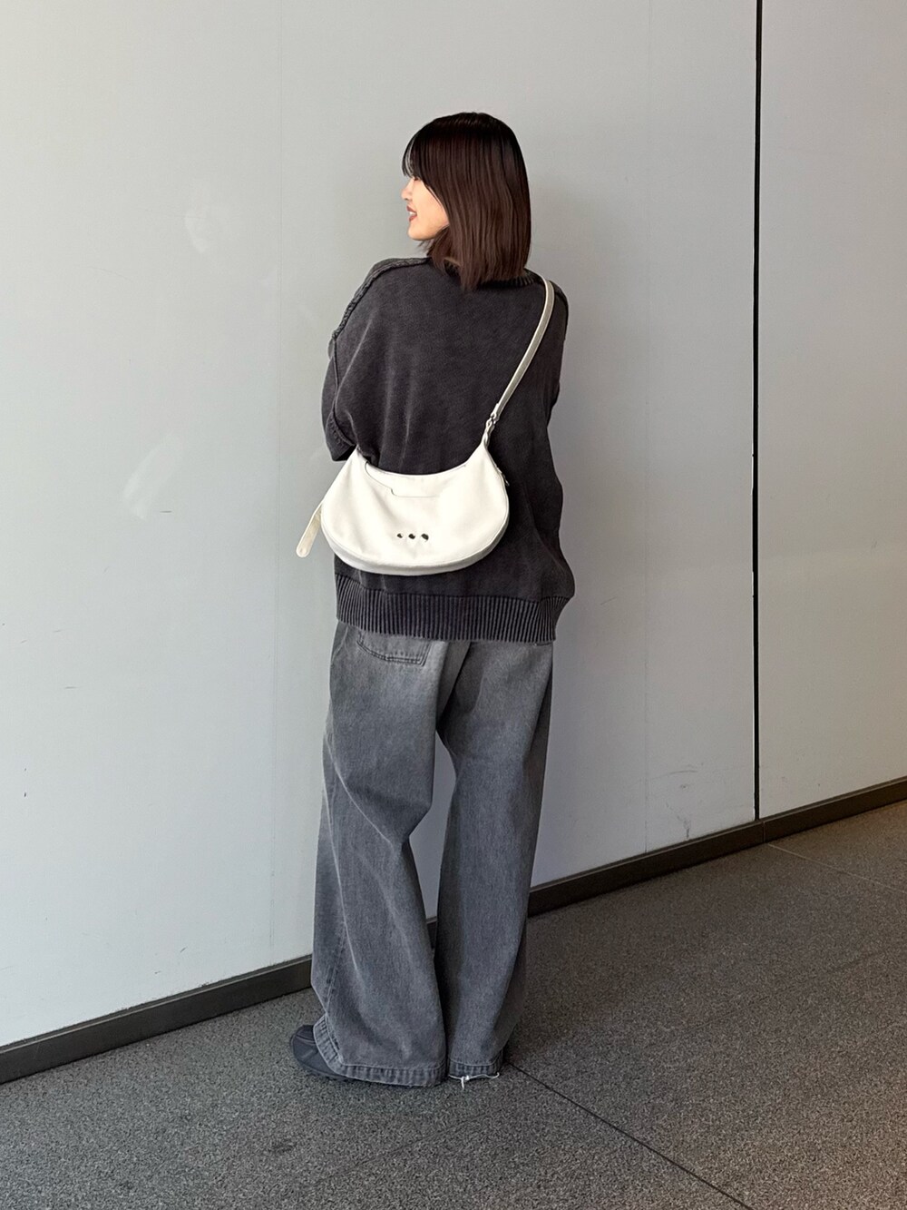 ブラック系のデニムパンツ、ブラック系のニット/セーター、ホワイト系のショルダーバッグを着用したレディースの秋コーディネートの3枚目の写真