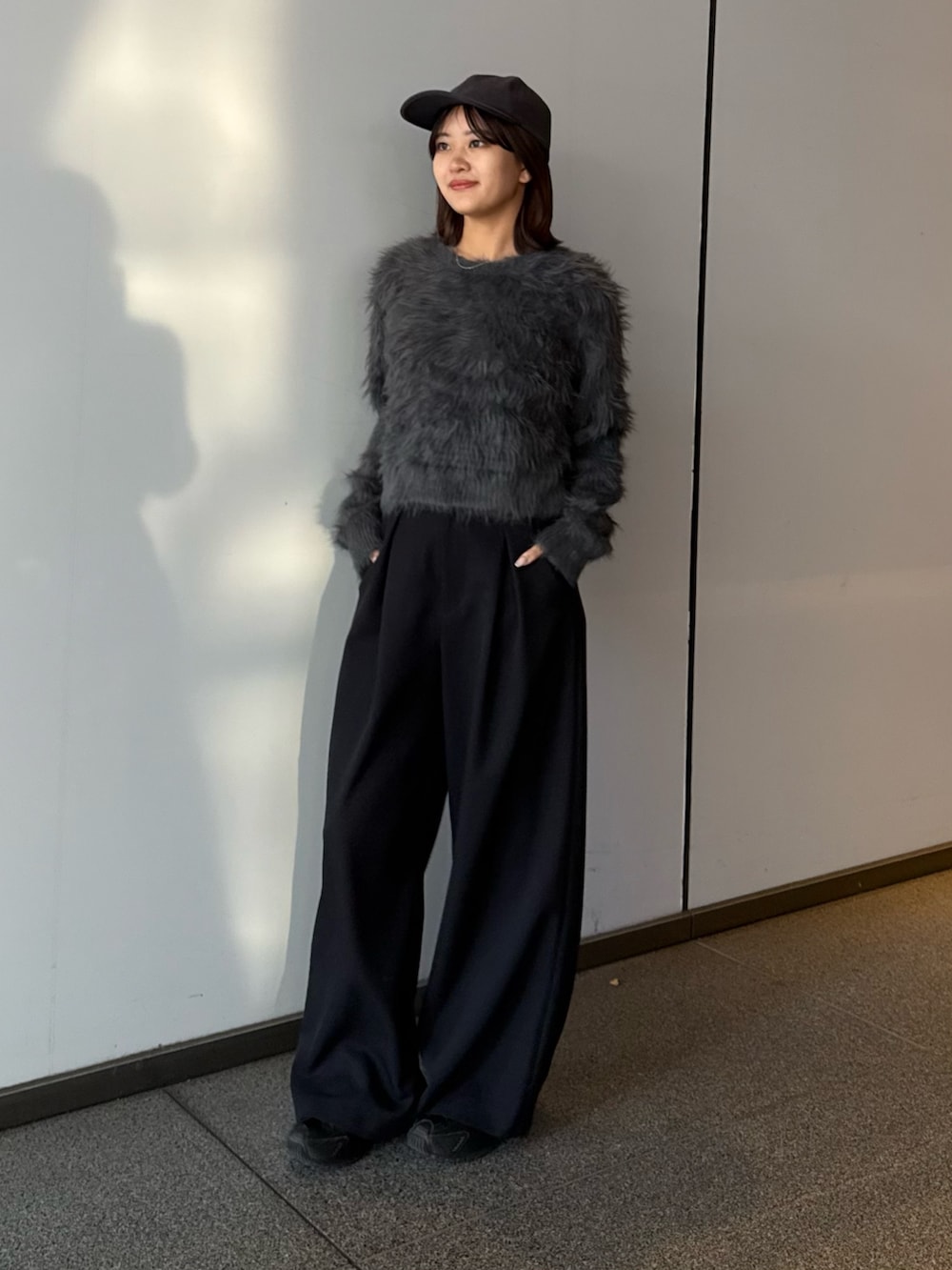 グレー系のニット/セーター、ブラック系のスラックスを着用したレディースの冬コーディネートの2枚目の写真