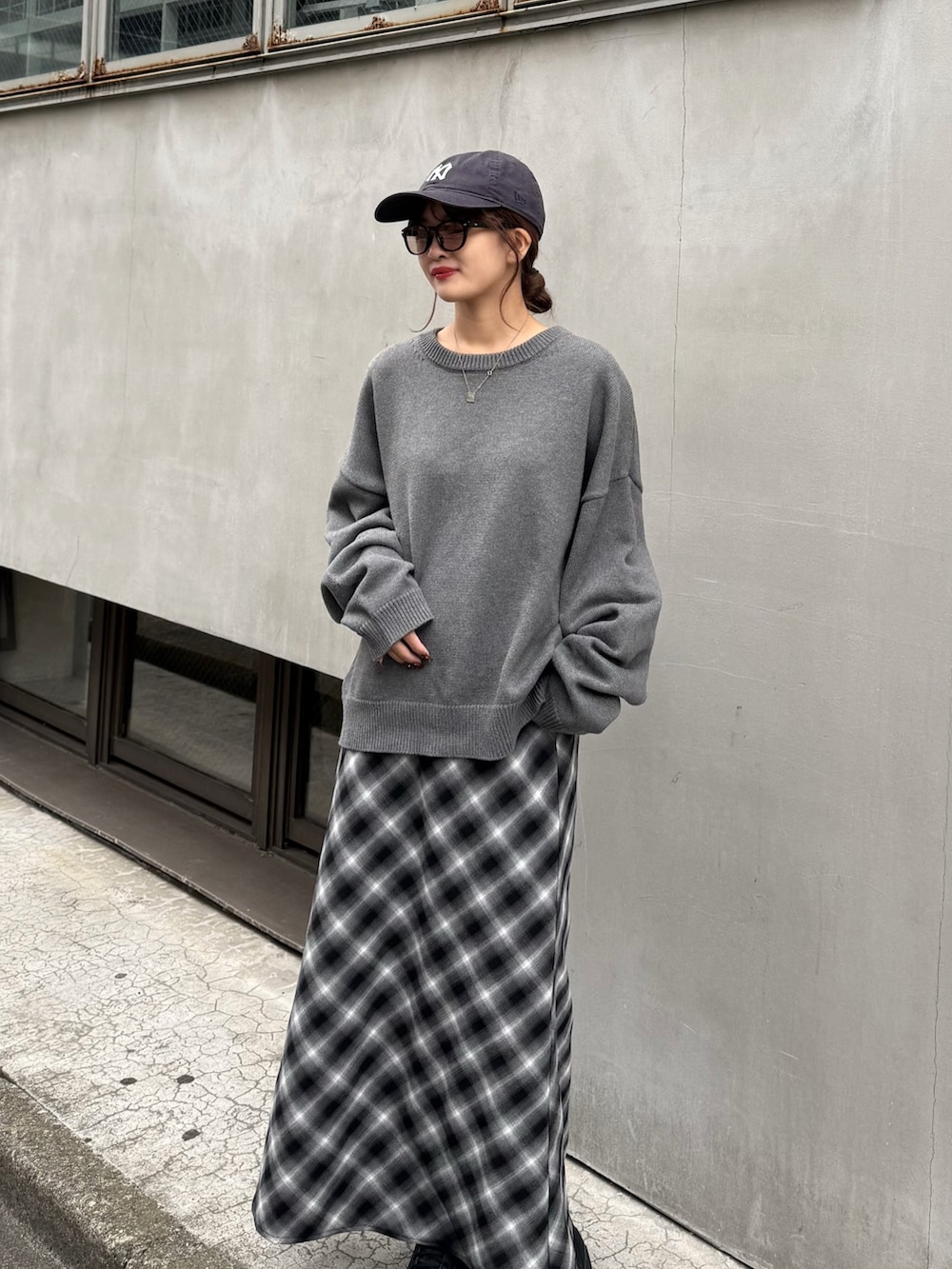 グレー系のニット/セーター、ブラック系のスカート、ブラック系のサングラスを着用したレディースの秋コーディネートの2枚目の写真