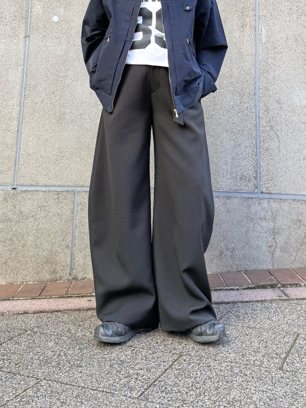 ブラック系のスラックス、ブルー系のブルゾン、ブラック系のサングラスを着用したレディースの冬コーディネートの7枚目の写真