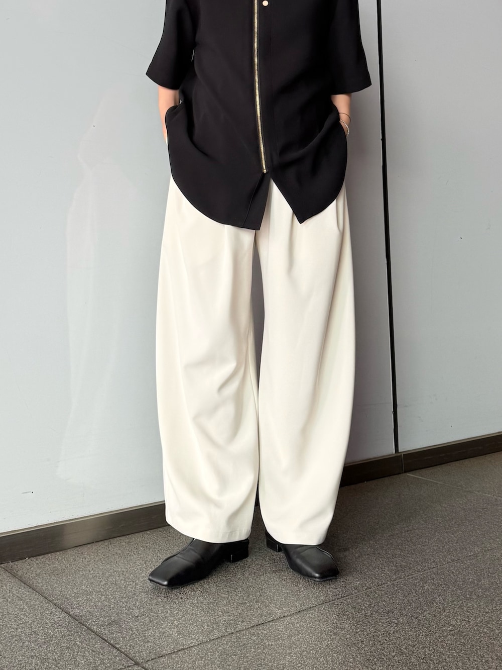 ブラック系のシャツ/ブラウス、グレー系のスラックスを着用したレディースの春コーディネートの6枚目の写真