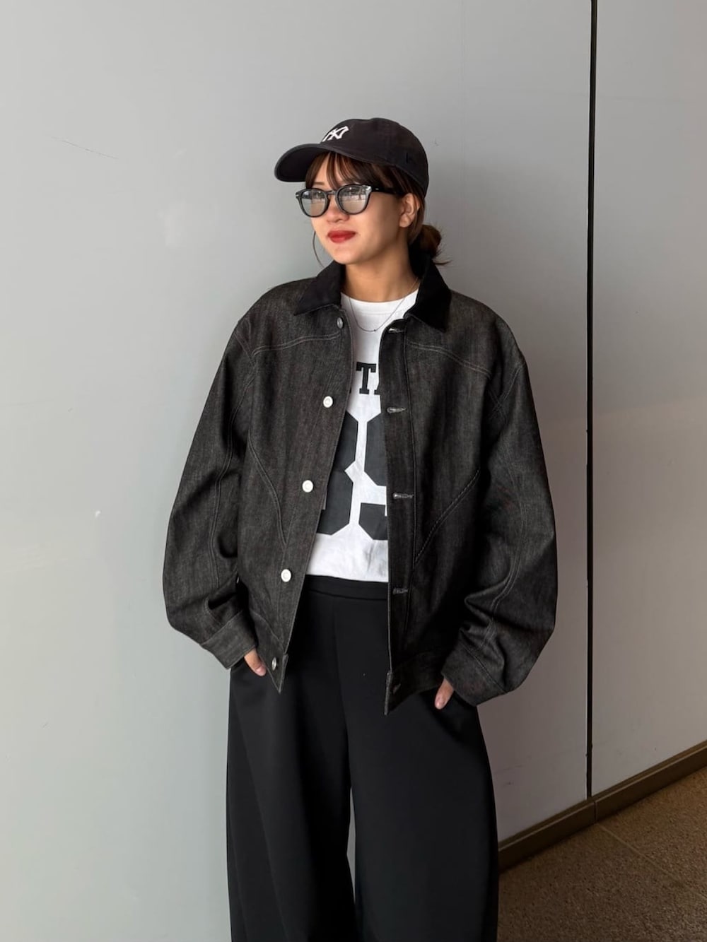 ブラック系のデニムジャケット、グレー系のその他パンツ、ブラック系のサングラスを着用したレディースの春コーディネートの2枚目の写真