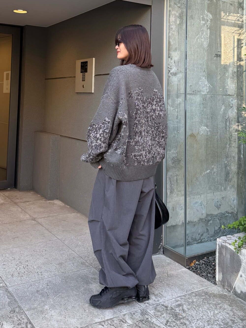 ブラック系のニット/セーター、グレー系のスラックス、ブラック系のハンドバッグを着用したレディースの冬コーディネートの5枚目の写真