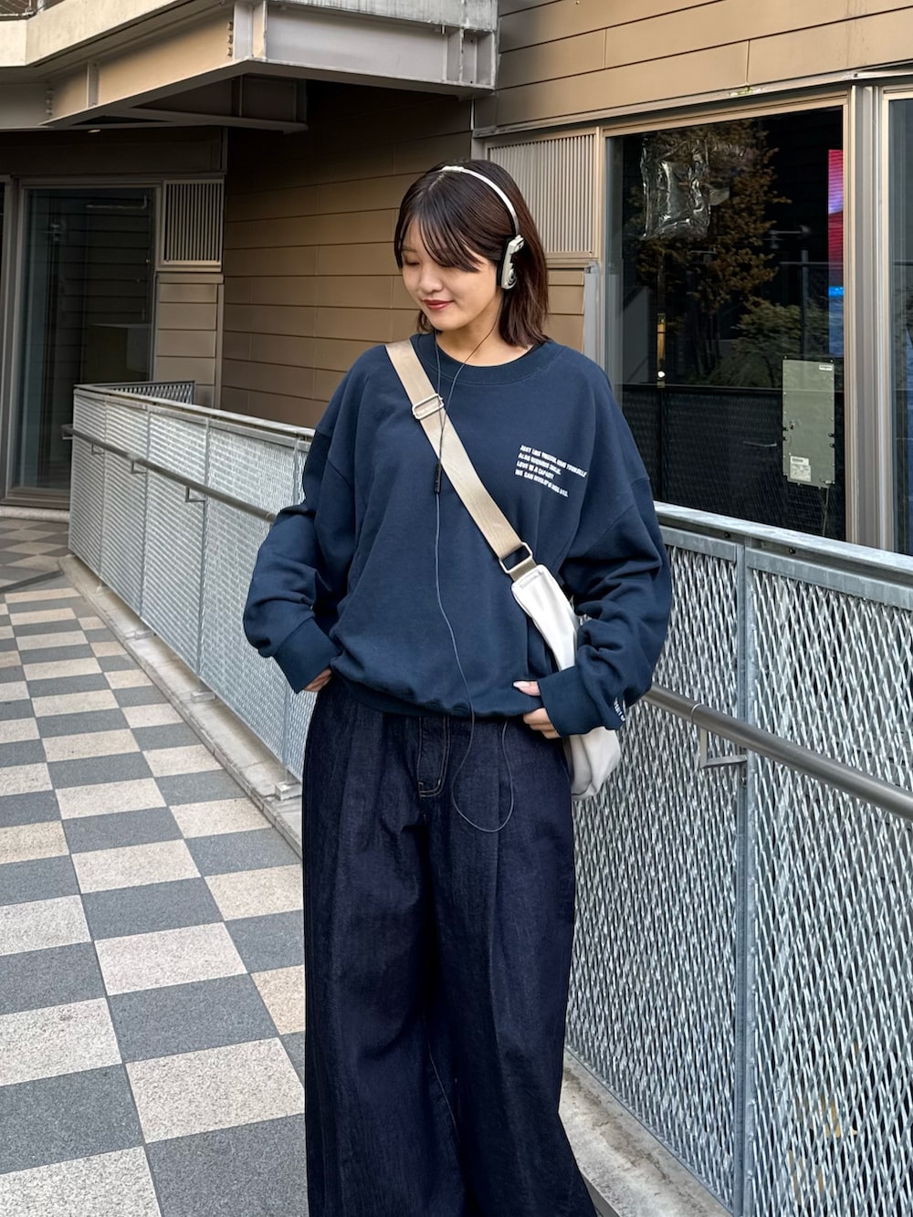 ブルー系のスウェット、グレー系のショルダーバッグ、ブルー系のデニムパンツを着用したレディースの冬コーディネートの6枚目の写真