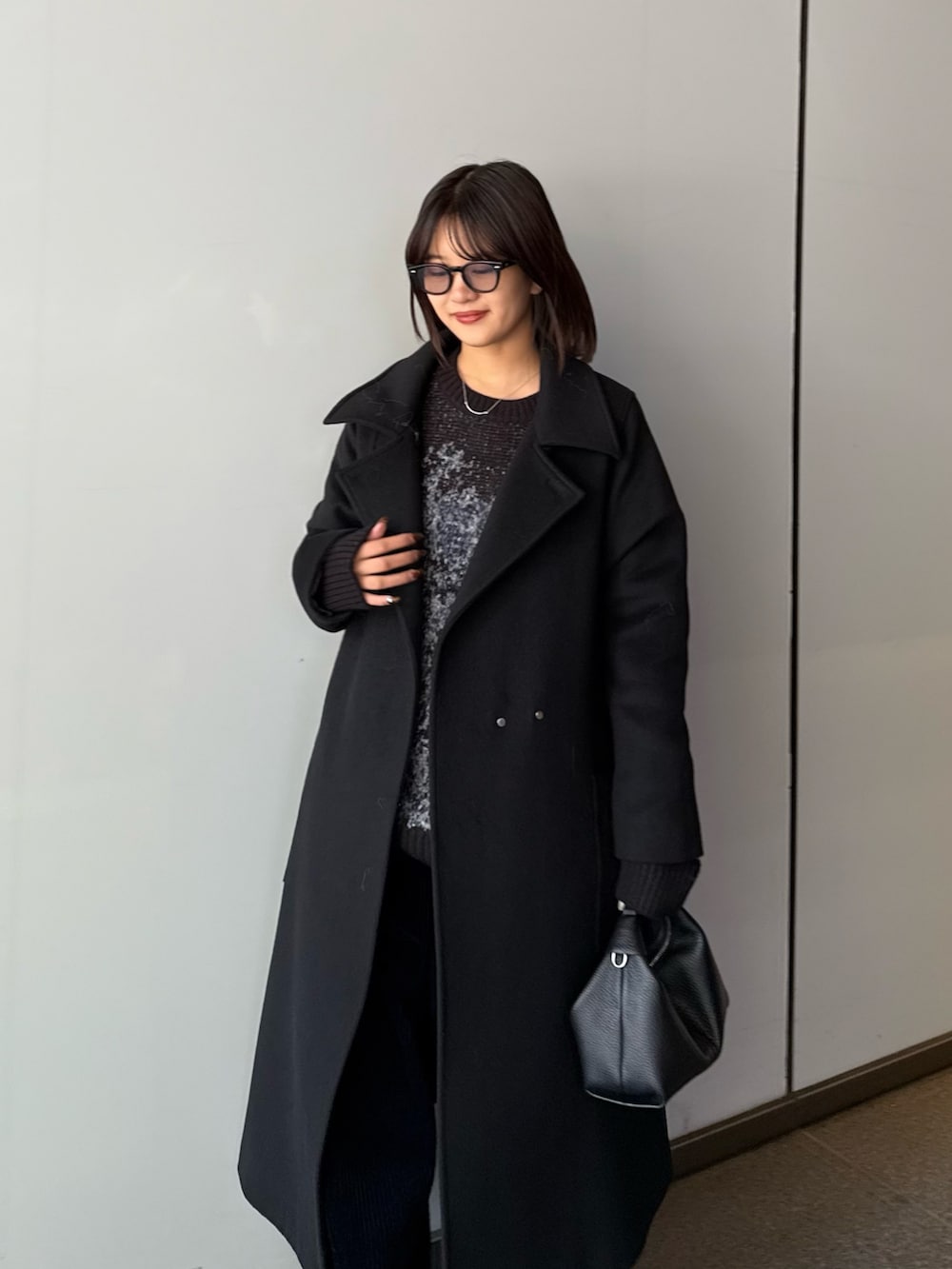 ブラック系のチェスターコート、ブラック系のニット/セーター、ブラック系のトートバッグを着用したレディースの秋コーディネートの5枚目の写真