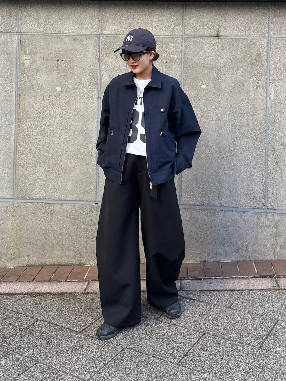 ブラック系のスラックス、ブルー系のブルゾン、ブラック系のサングラスを着用したレディースの冬コーディネートの2枚目の写真