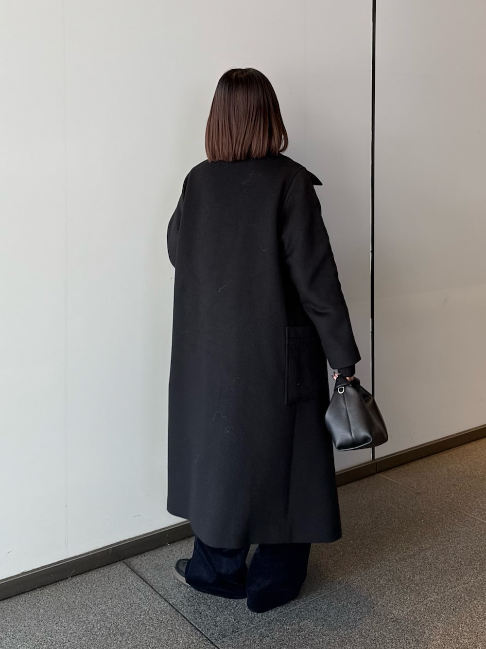 ブラック系のチェスターコート、ブラック系のニット/セーター、ブラック系のトートバッグを着用したレディースの秋コーディネートの4枚目の写真