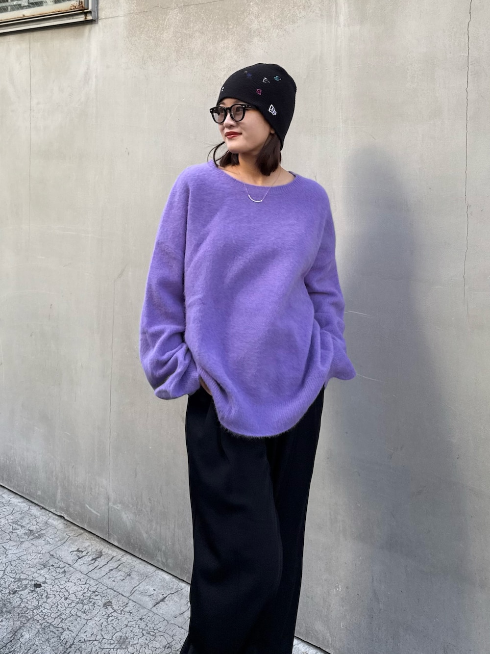 パープル系のニット/セーター、ブラック系のスラックス、ブラック系のサングラスを着用したレディースの秋コーディネートの3枚目の写真