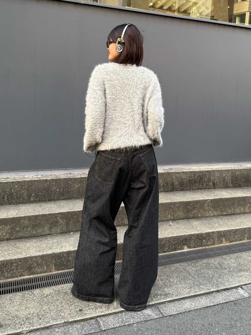 グレー系のニット/セーター、ブラック系のデニムパンツを着用したレディースの秋コーディネートの4枚目の写真