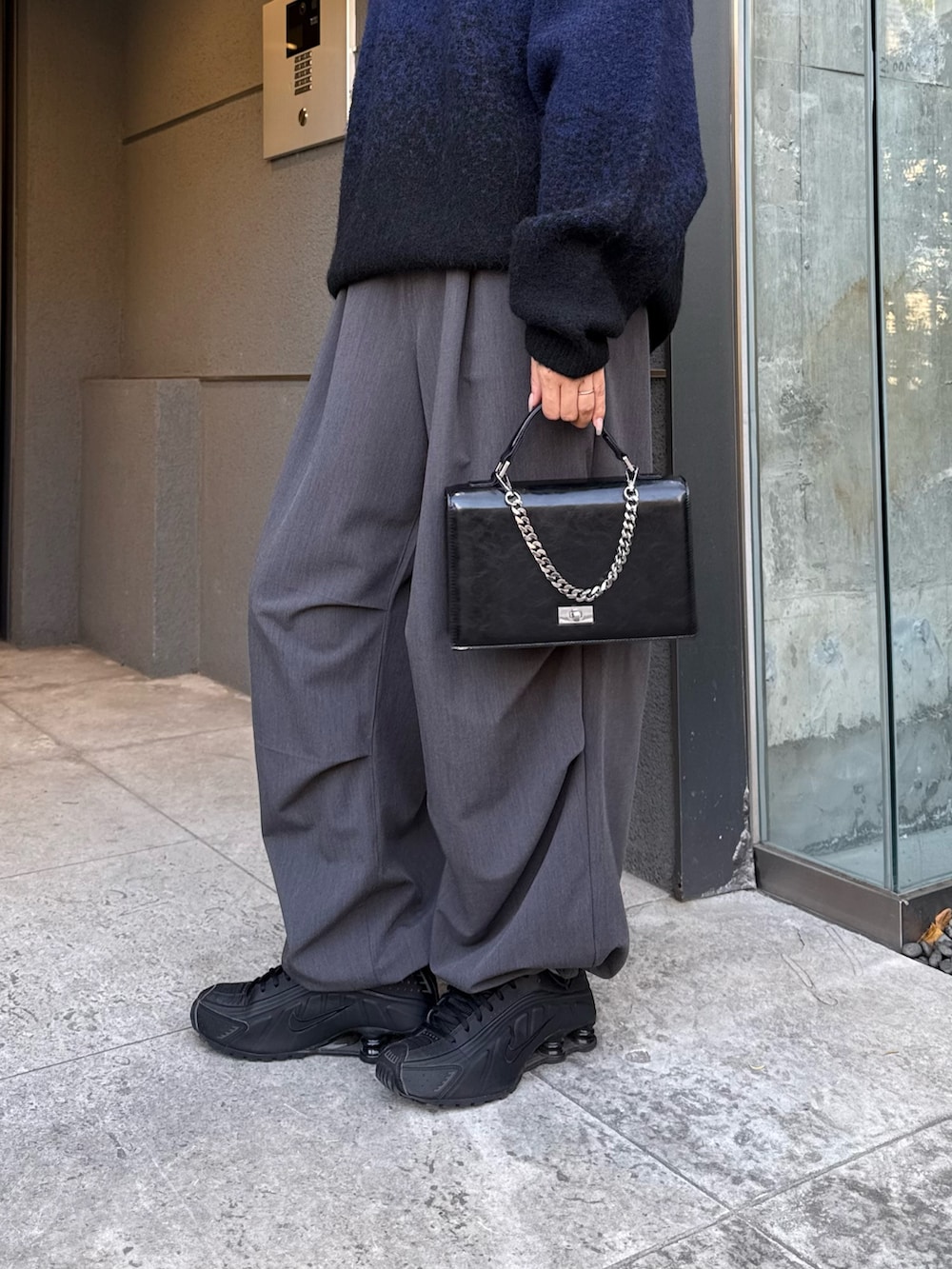ブラック系のニット/セーター、グレー系のスラックス、ブラック系のショルダーバッグを着用したレディースの冬コーディネートの5枚目の写真
