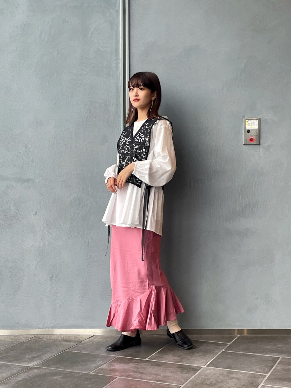 ブラック系のシャツ/ブラウス、ピンク系のスカート、ブラック系のパンプスを着用したレディースの春コーディネートの2枚目の写真