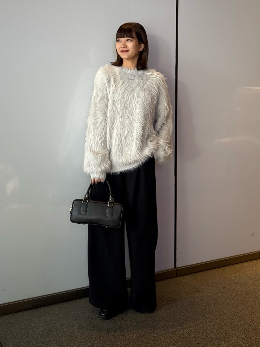 ブラック系のスラックス、ブラック系のトートバッグ、グレー系のニット/セーターを着用したレディースの冬コーディネートの2枚目の写真