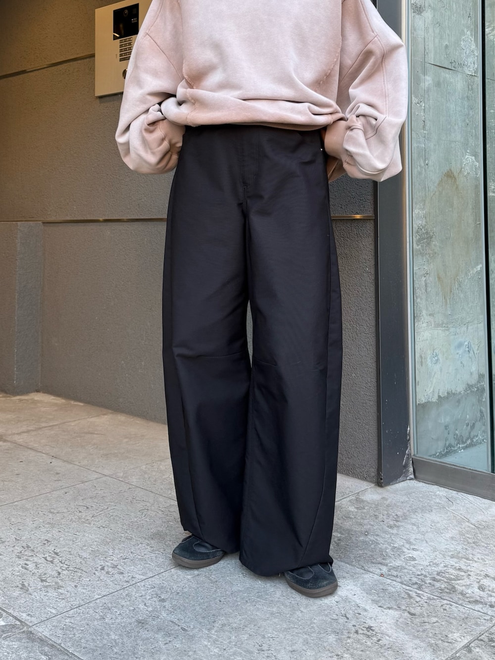 ベージュ系のスウェット、ブラック系のスラックス、ブラック系のサングラスを着用したレディースの冬コーディネートの7枚目の写真