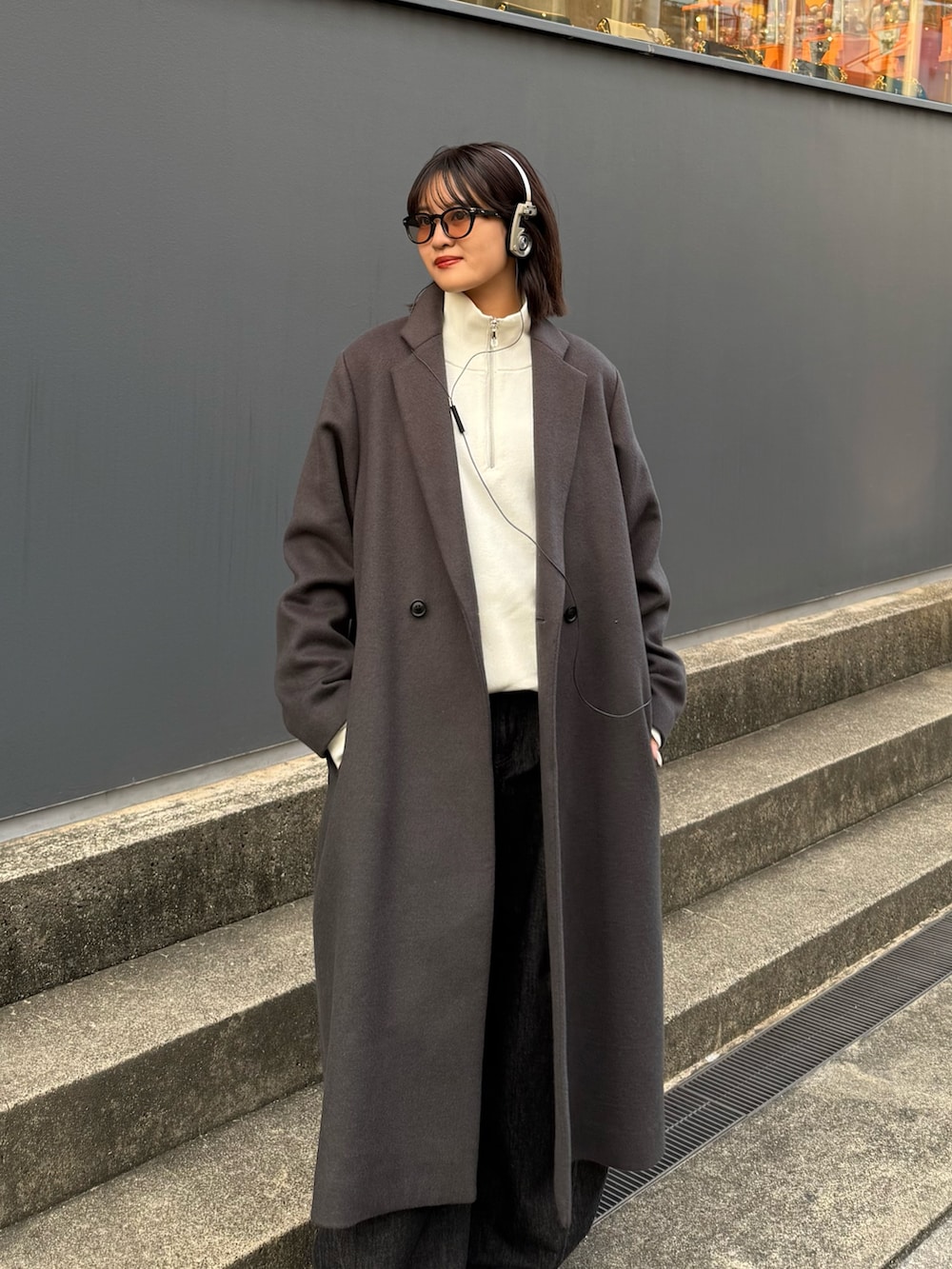 グレー系のチェスターコート、ホワイト系のニット/セーター、ブラック系のデニムパンツを着用したレディースの秋コーディネートの3枚目の写真