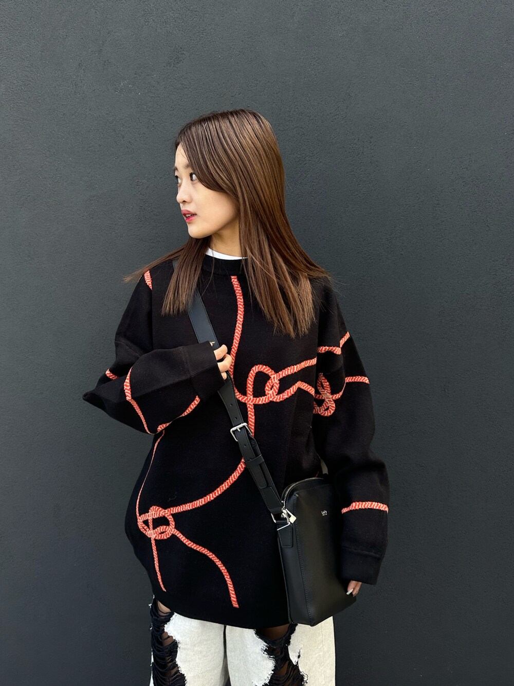 ブラック系のニット/セーター、ブラック系のショルダーバッグ、ブルー系のデニムパンツを着用したレディースの冬コーディネートの4枚目の写真