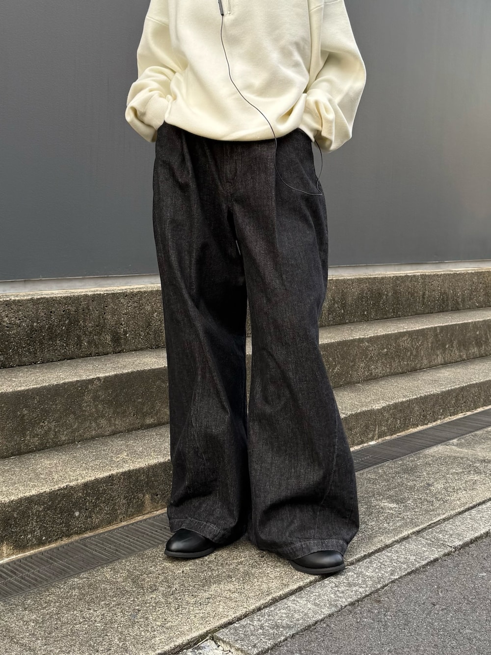 グレー系のチェスターコート、ホワイト系のニット/セーター、ブラック系のデニムパンツを着用したレディースの秋コーディネートの7枚目の写真