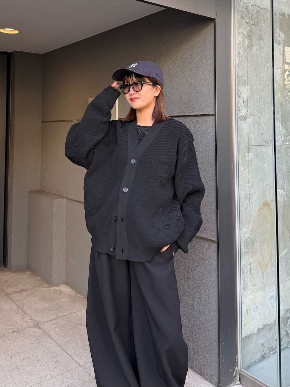 ブラック系のスラックス、ブラック系のカーディガン/ボレロ、ブラック系のサングラスを着用したレディースの冬コーディネートの4枚目の写真