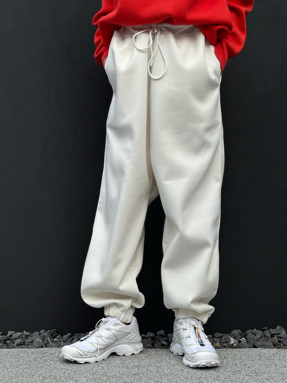 ホワイト系のスウェットパンツ、オレンジ系のニット/セーター、ホワイト系のスニーカーを着用したレディースの秋コーディネートの5枚目の写真