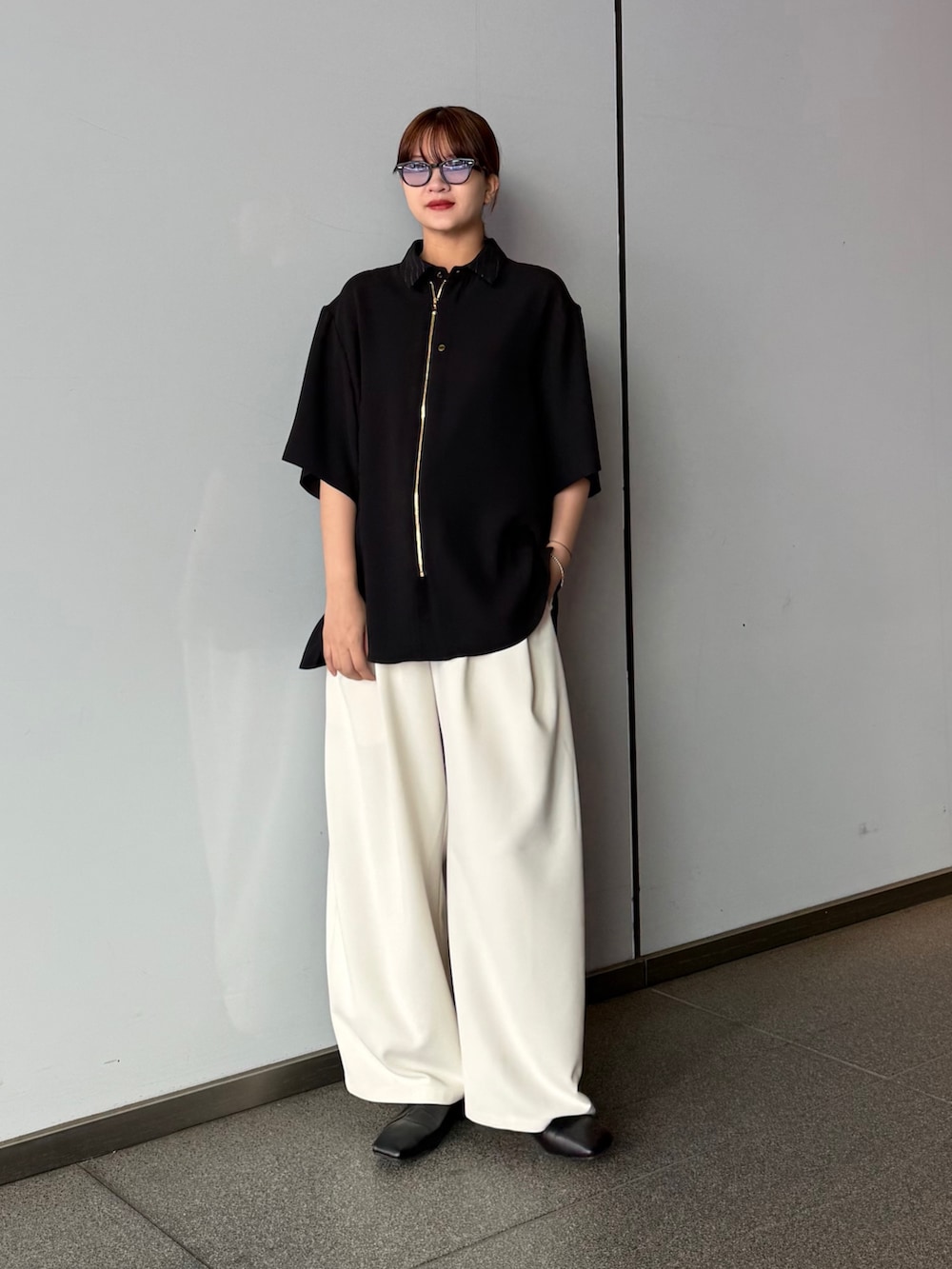 ブラック系のシャツ/ブラウス、グレー系のスラックスを着用したレディースの春コーディネートの2枚目の写真