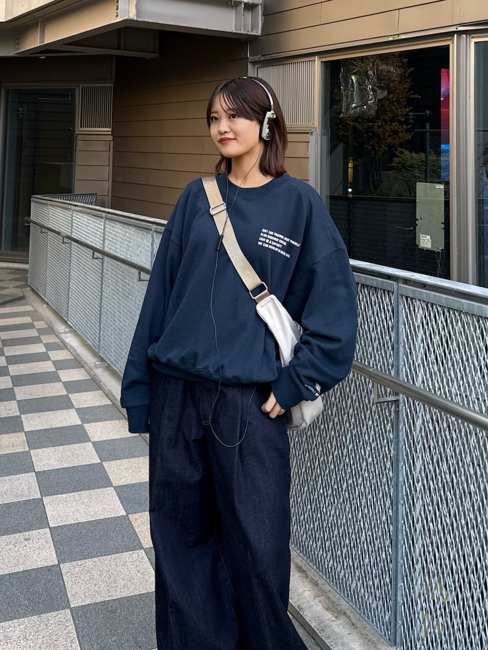 ブルー系のスウェット、グレー系のショルダーバッグ、ブルー系のデニムパンツを着用したレディースの冬コーディネートの5枚目の写真