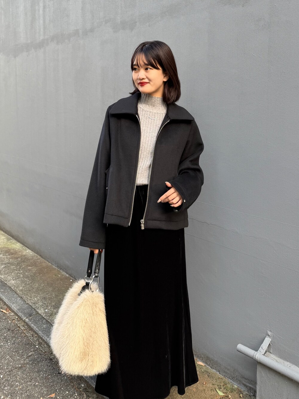 ブラック系のスカート、ブラウン系のトートバッグ、ブラック系のブルゾンを着用したレディースの秋コーディネートの2枚目の写真