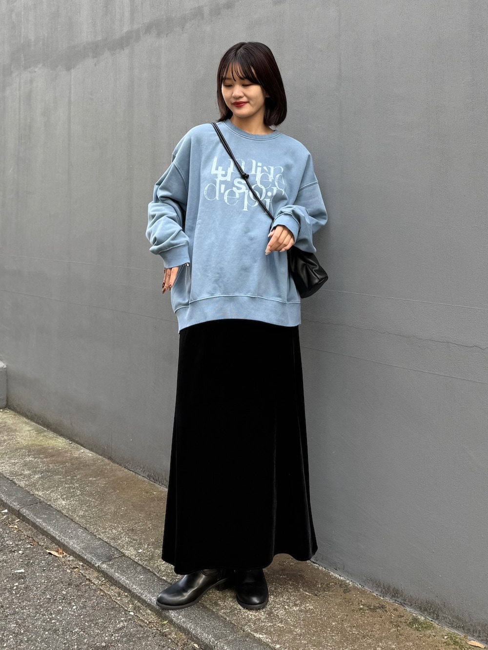 ブラック系のショルダーバッグ、ブルー系のスウェット、ブラック系のスカートを着用したレディースの秋コーディネートの2枚目の写真