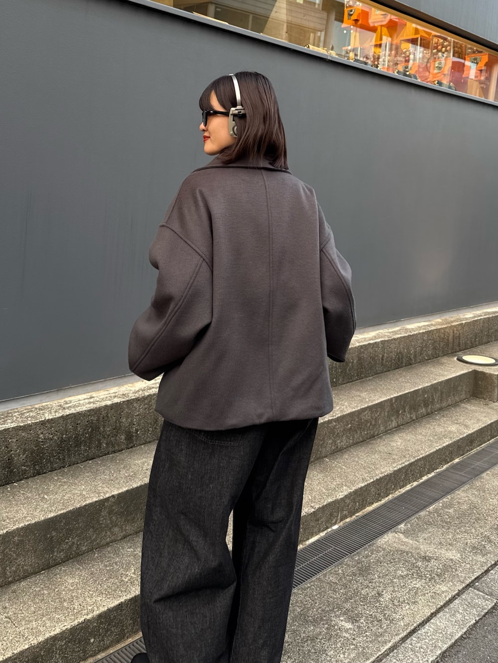 グレー系のブルゾン、レッド系のカーディガン/ボレロ、ブラック系のデニムパンツを着用したレディースの秋コーディネートの5枚目の写真