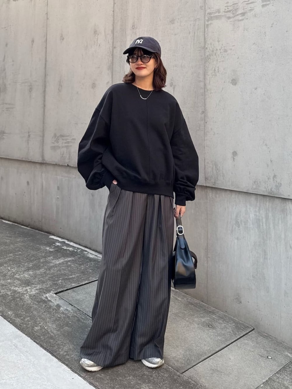 ホワイト系のスウェット、グレー系のスラックス、ブラック系のハンドバッグを着用したレディースの冬コーディネートの2枚目の写真