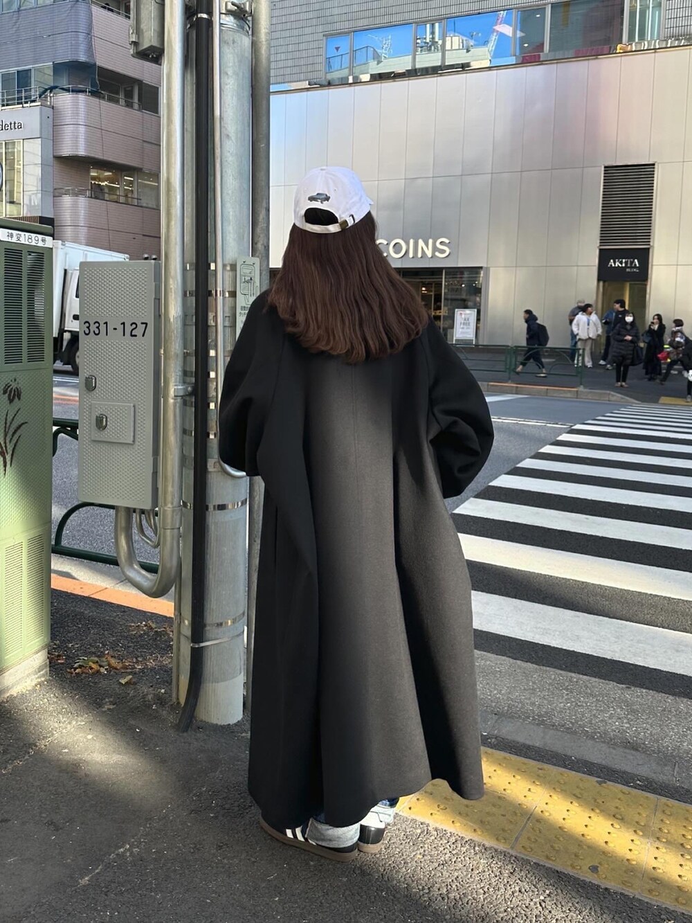 ブラック系のステンカラーコートを着用したレディースの冬コーディネートの2枚目の写真