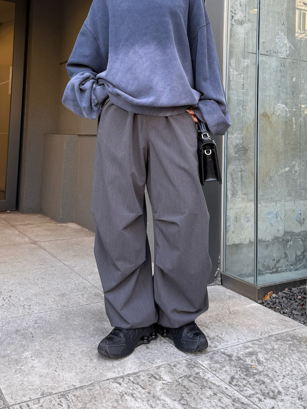 ブルー系のスウェット、ブラック系のショルダーバッグ、グレー系のスラックスを着用したレディースの冬コーディネートの5枚目の写真