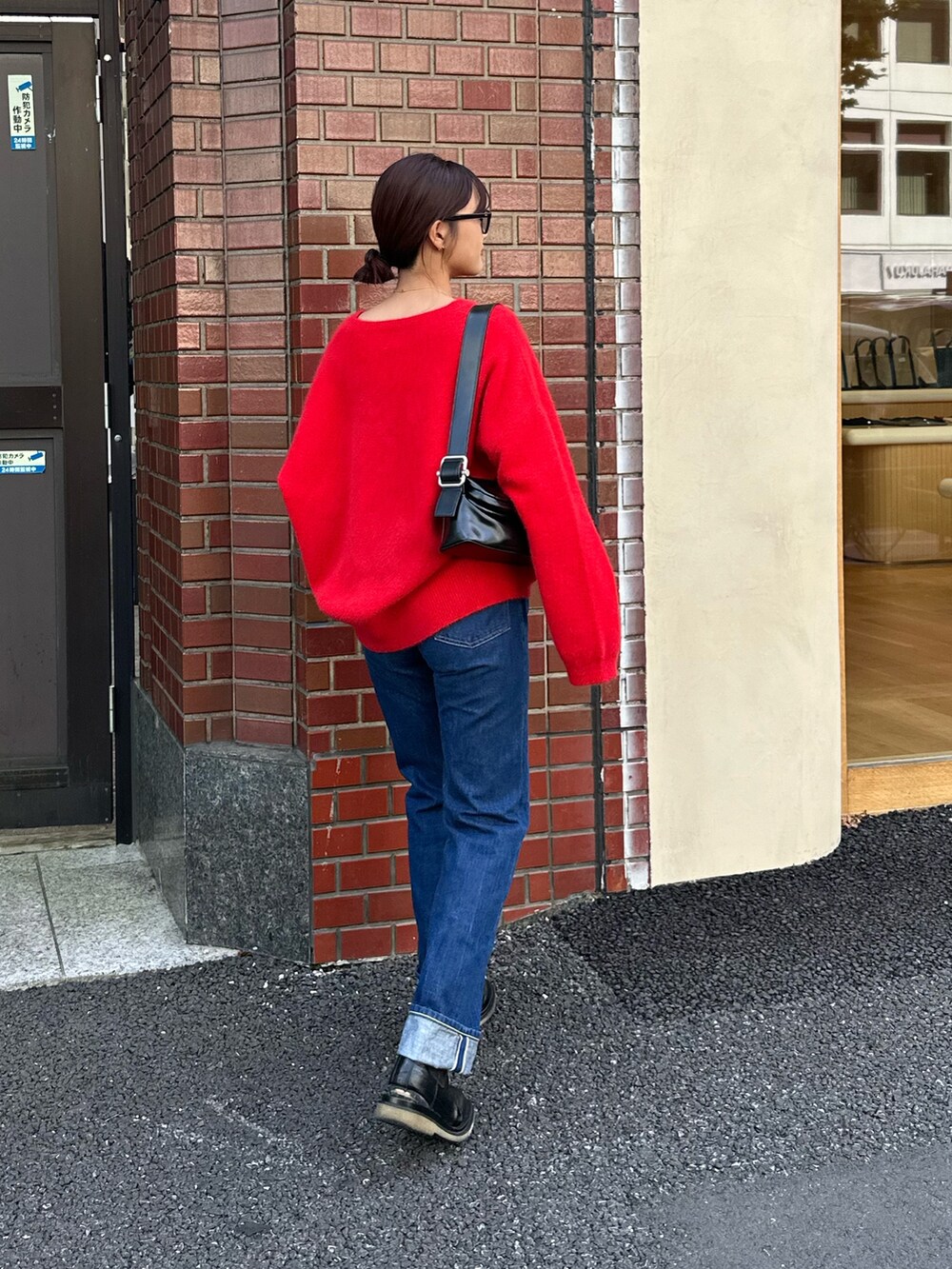 レッド系のニット/セーター、ブラック系のショルダーバッグ、グレー系のサングラスを着用したレディースの秋コーディネートの2枚目の写真