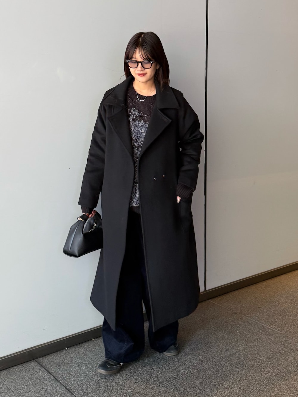 ブラック系のチェスターコート、ブラック系のニット/セーター、ブラック系のトートバッグを着用したレディースの秋コーディネートの3枚目の写真