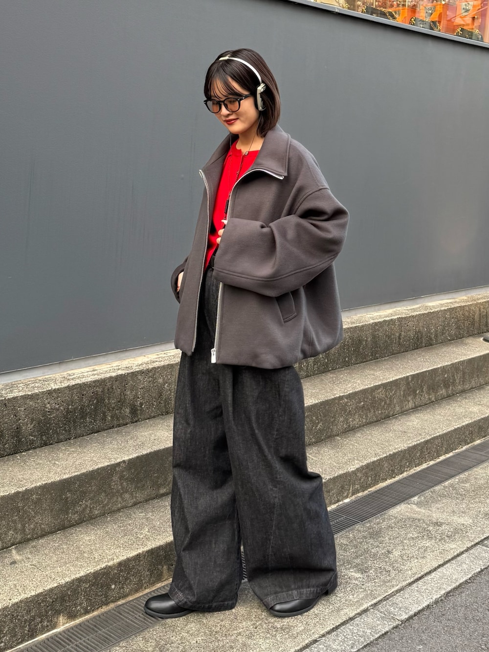 グレー系のブルゾン、レッド系のカーディガン/ボレロ、ブラック系のデニムパンツを着用したレディースの秋コーディネートの7枚目の写真